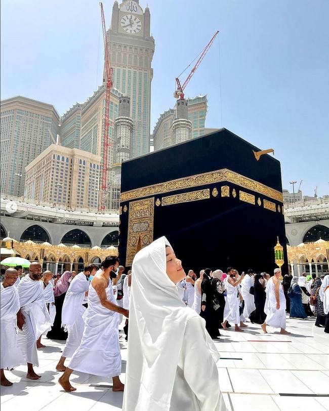 Saat umrah, Fuji mengenakan abaya polos dan hijab syari warna putih. Fuji memakai inner hijab warna hitam agar bagian depan rambutnya tak terlihat. Ia berpose tepat di depan Kabah. Foto: Dok. Instagram @fuji_an.