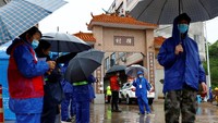 Sejumlah orang berdiri di saat mobil polisi memasuki pos pemeriksaan di Desa Lu yang berada di dekat lokasi jatuhnya pesawat Boeing 737-800 milik maskapai China Eastern Airlines di wilayah Guangxi, China, Rabu (23/3/2022). REUTERS/CARLOS GARCIA RAWLINS.