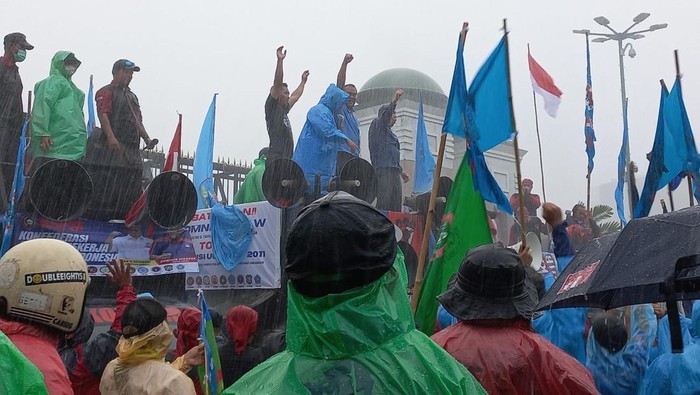 Massa aksi tolak UU Cipta Kerja bertahan di depan Gedung DPR RI meski dalam kondisi hujan deras.