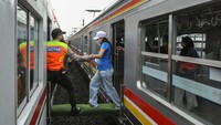 Dengan dibantu jembatan darurat, para penumpang berpindah kereta.