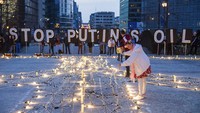 Seorang wanita berdiri di dekat seberkas lampu dan lilin saat dinyalakan di sekitar tanda perdamaian raksasa. (AP/Geert Vanden Wijngaert)