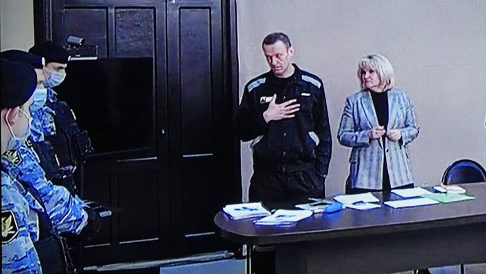 Tokoh Oposisi Rusia Alexei Navalny Divonis 9 Tahun Penjara Russian opposition leader Alexei Navalny, centre, gestures via a video link provided by the Russian Federal Penitentiary Service, standing next to his layer and speaking with Penitentiary Service officers during a court session, in Pokrov, Vladimir region, about 100 kilometers (62 miles) east of Moscow, Russia, Tuesday, March 22, 2022. Navalny has been convicted of fraud and contempt of court and sentenced to nine years in a maximum security prison. A judge also ruled Tuesday that Navalny would have to pay a fine of 1.2 million rubles (about $11,500). (AP Photo/Alexander Zemlianichenko)