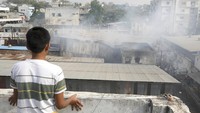 Seseorang melihat dari ketinggian saat petugas pemadam kebakaran mencoba memadamkan api yang berkobar di gudang bekas di Hyderabad, India.