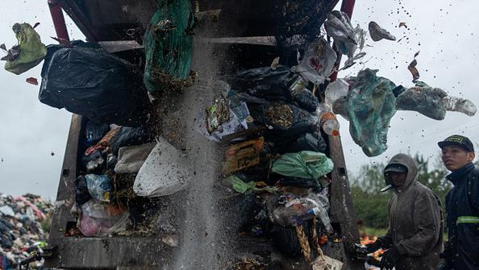 Mencari Nafkah di Tempat Pembuangan Sampah Terbesar Argentina LUJAN, ARGENTINA - MARCH 23: Men work as garbage falls from a garbage truck to sort and sell its residues on March 23, 2022 in Lujan, Argentina. Despite the official announcements of a plan to reconvert the biggest garbage dump of Argentina into a recycling and waste treatment center, the surrounding areas of Lujan, in the outskirts of the city of Buenos Aires, continue to be hit pollution. While some residents are sceptical on the viability of the project, funded by the Inter-American Development Bank, others worry about a potential loss of their source of income. An estimate of 150 families struggle to make a living collecting rubbish from this open-air dump of over 12 hectares where 120 tons of waste are thrown, feeding mountains of rubbish up to 30 meters. (Photo by Tomas Cuesta/Getty Images)