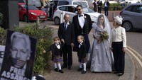 Moris berpose untuk foto bersama dia dan dua putra Assange yang masih kecil saat mereka tiba di luar penjara. Dia mengenakan gaun pengantin dan kerudung bersulam pesan dari teman dan keluarga. Gaun itu dirancang oleh desainer Inggris Vivienne Westwood, yang merupakan salah satu pendukung Assange yang lebih vokal dan terkenal. Westwood juga mendesain rok tartan untuk Assange. (AP/Matt Dunham)