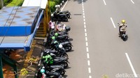 Para driver ojol terlihat duduk di halte sambil berbincang. Sebagian besar driver ojol memarkirkan motor di depan halte yang berada di depan Plaza Senayan sambil menunggu orderan.