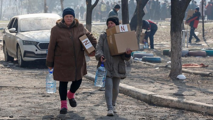 Warga Mariupol Antre Panjang untuk Terima Bantuan Makanan Local residents carry humanitarian aid delivered by Russian soldiers during Ukraine-Russia conflict, in the besieged southern port of Mariupol, Ukraine March 23, 2022. REUTERS/Alexander Ermochenko