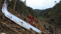 Bagian-bagian jenazah itu ditemukan di antara puing-puing pesawat. (AP Photo/Jiang Huaipeng) 