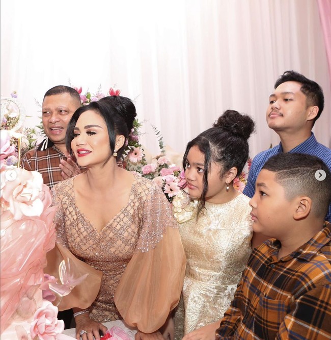 Krisdayanti tampil cantik dalam balutan gaun berwarna coklat dengan tangan model balon. Raul Lemos, Amora, dan Kellen pun mengenakan pakaian yang senada dengan Krisdayanti. Raul dan Kellen tampak mengenakan kemeja kotak-kotak berwarna coklat, sedangkan Amora tampil dalam balutan gaun berwarna emas. Foto: Instagram