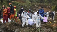 Dalam foto yang dirilis oleh Kantor Berita Xinhua, petugas membawa kotak yang diyakini berisi barang-barang milik korban pesawat Boeing 737-800, Kamis (24/3/2022). Pesawat itu milik maskapai China Eastern Airlines yang jatuh di wilayah Guangxi, China. (Lu Boan/Xinhua via AP).