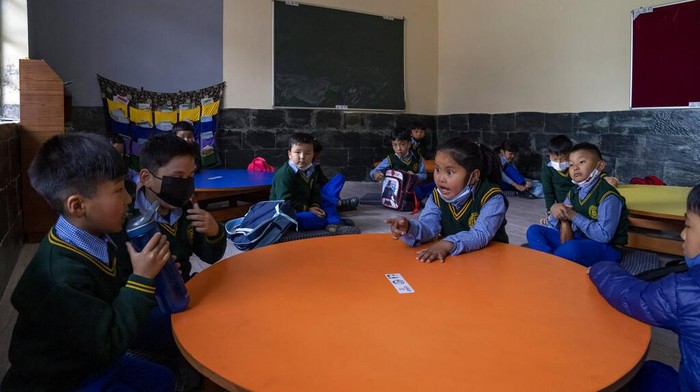 An exile Tibetan child bites into an apple while hanging upside down from iron bars during a break in classes at the Tibetan Children's Village Day School in Dharmsala, India. Thursday, March 24, 2022. The school life is slowly returning to normal after disruptions due to the COVID-19 pandemic. (AP Photo/Ashwini Bhatia)