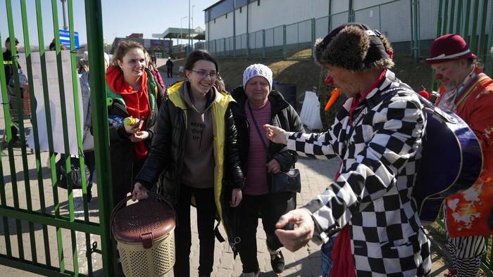 Potret Badut Medis Hibur Anak-anak Pengungsi Ukraina Ukrainian Margarita Zacepina is entertained by Nimrod Eisenberg, a clown from the Dream Doctors organization from Israel, at the border crossing in Medyka, southeastern Poland, on Thursday, March 24, 2022. Medical clowns were in action on Thursday at the Medyka border crossing between Ukraine and Poland to cheer up refugee children and also their parents, and bring a temporary relief from the psychological traumas caused by war and separation. (AP Photo/Sergei Grits)