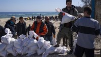 Relawan bergantian mengangkut kantong pasir di Pantai Odesa. Pada saat damai, pantai ini menjadi pusat turis di kawasan Ukraina selatan.  (AP Photo/Petros Giannakouris)