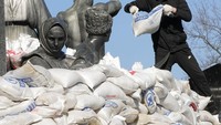 Warga kota menutup patung penyair dan simbol pemersatu nasional,  Taras Shevchenko, menggunakan kantong pasir di Kharkiv, Ukraina, Kamis (24/3/2022).  (AP Photo/Efrem Lukatsky)