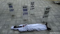 Pendemo dengan pakaian pocong menggelar teaterikal yang menggambarkan matinya udara bersih.