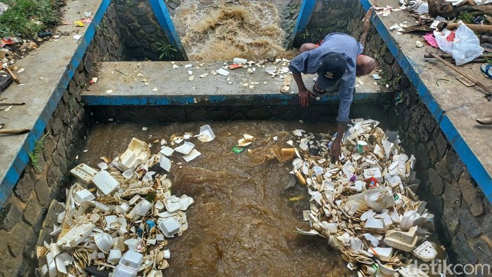 Cece tengah mengais sampah dengan menggunakan tangan di Sungai Cirasea