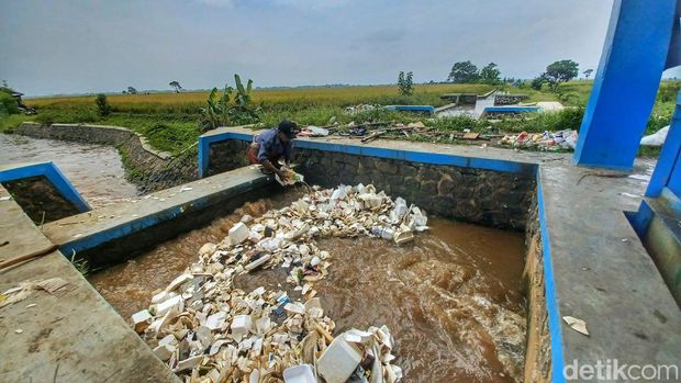Cece tengah mengais sampah dengan menggunakan tangan di Sungai Cirasea