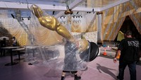 Pekerja Derek Smith membawa patung Oscar di sepanjang karpet merah saat persiapan Academy Awards sedang berlangsung di Los Angeles, California, AS. REUTERS/Mike Blake