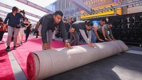 Para pekerja menggelar karpet merah di Hollywood Boulevard saat persiapan Academy Awards dimulai di Los Angeles, (23/3/2022), California, AS. REUTERS/Mike Blake