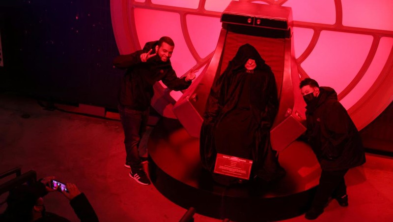 A person takes a selfie with a life-size figure of Darth Vader at 