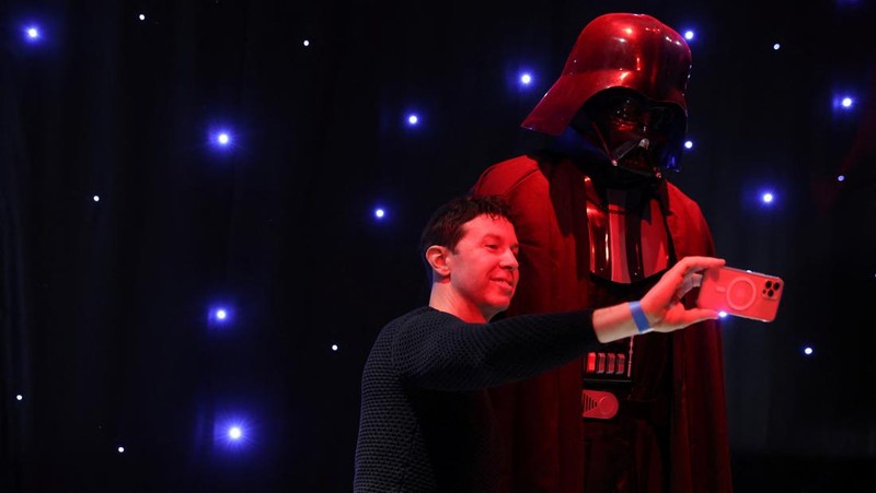 A person takes a selfie with a life-size figure of Darth Vader at 