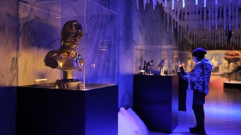 Seseorang berjalan di antara pajangan di The Fans Strike Back: The Largest Star Wars Fan Exhibition.