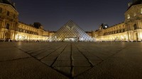 Lampu yang biasanya menerangi piramida di Museum Louvre, Paris, Prancis, tampak dimatikan saat peringatan Earth Hour, Sabtu (26/3/2022). REUTERS/Christian Hartmann. 