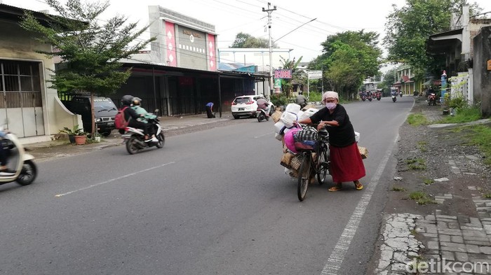 Tri Wahyuni Parangtritis mendorong sepeda berisi puluhan keranjang bunga bekas untuk dijual.