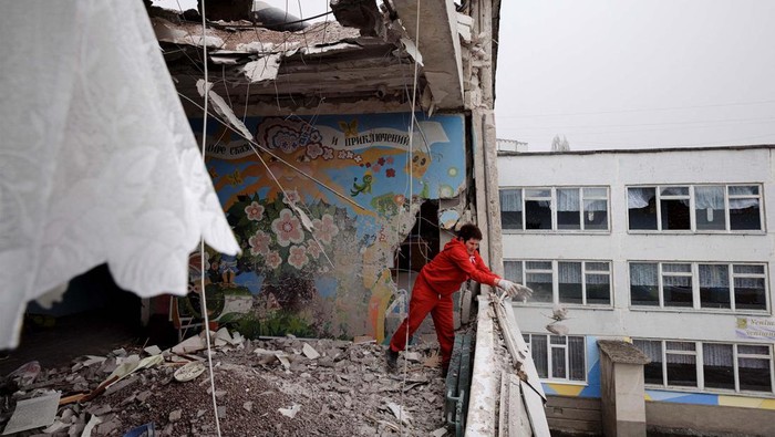 Sekelompok wanita beraksi membersihkan puing-puing dari bangunan sekolah di Kharkiv, Ukraina. Sekolah ini rusak setelah menjadi sasaran penembakan oleh militer Rusia.