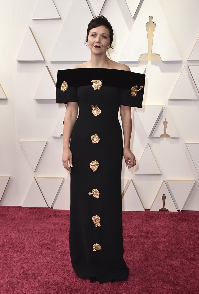 Gaun hitam nan unik dari koleksi Schiaparelli Couture Spring-Summer 2022 membungkus tubuh Maggie Gyllenhaal. Dirancang oleh Daniel Roseberry, gaun bergaya kontemporer itu dihiasi kepingan ukiran emas. (Foto: Jordan Strauss/Invision/AP)