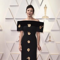 Gaun hitam nan unik dari koleksi Schiaparelli Couture Spring-Summer 2022 membungkus tubuh Maggie Gyllenhaal. Dirancang oleh Daniel Roseberry, gaun bergaya kontemporer itu dihiasi kepingan ukiran emas. (Foto: Jordan Strauss/Invision/AP)