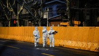 Staf medis dengan alat pelindung diri (APD) berjalan di depan penghalang area yang dikunci, di tengah pandemi penyakit coronavirus (COVID-19), di Shanghai, China.