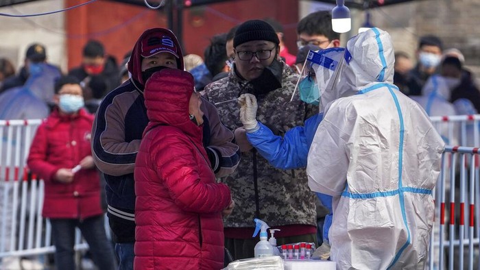 Residents line up for a coronavirus test inside barricaded residential buildings locked down for monitoring following a COVID-19 case detected in the area Monday, March 28, 2022, in Beijing. China began its largest lockdown in two years Monday to conduct mass testing and control a growing outbreak in its largest city of Shanghai as questions are raised about the economic toll of the nation's 