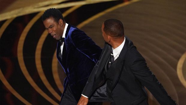 Will Smith, right, hits presenter Chris Rock on stage while presenting the award for best documentary feature at the Oscars on Sunday, March 27, 2022, at the Dolby Theatre in Los Angeles. (AP Photo/Chris Pizzello)
