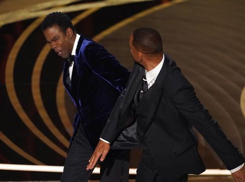 Will Smith, right, hits presenter Chris Rock on stage while presenting the award for best documentary feature at the Oscars on Sunday, March 27, 2022, at the Dolby Theatre in Los Angeles. (AP Photo/Chris Pizzello)