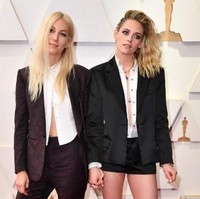 Kristen memadankan kemeja putihnya dengan blazer dan celana pendek hitam. Wanita yang menerima nominasi Oscars 2022 itu memakai high heels hitam untuk memberikan detail feminin pada penampilannya. Foto: AFP/ANGELA WEISS