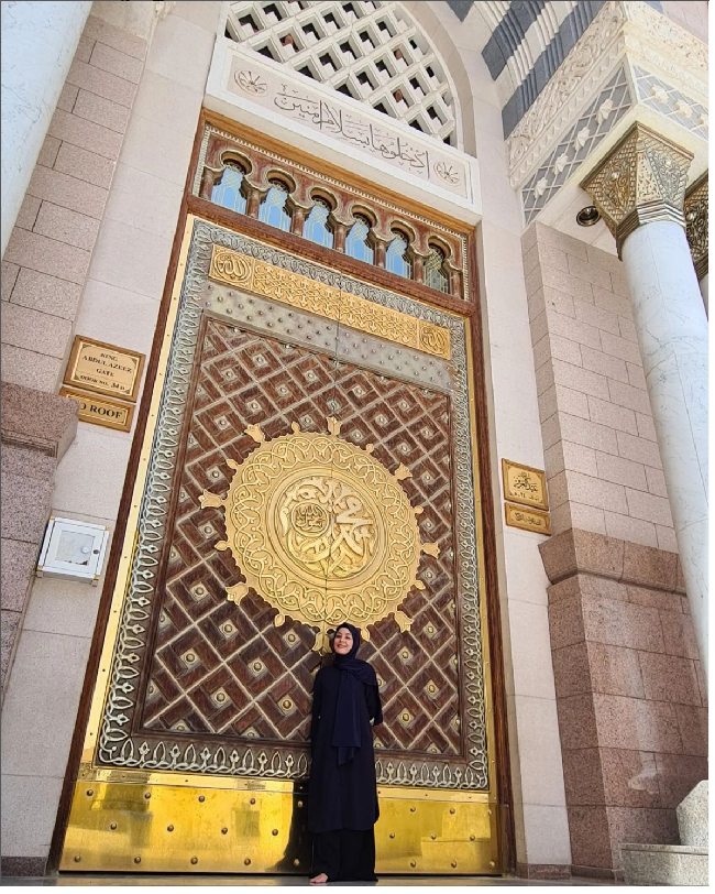 Berpose di depan pintu Masjid Nabawi, Madinah, Lulu Tobing tampil manglingi saat umrah dengan abaya dan hijab hitam. Foto: Dok. Instagram @lutob
