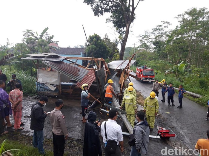Petugas PLN mengevakuasi tiang listrik yang menimpa warung bakso.