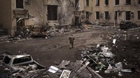 Seorang prajurit Ukraina berjalan di luar gedung administrasi regional yang rusak berat setelah serangan Rusia awal bulan ini di Kharkiv, Ukraina, Minggu, (27/3/2022). (AP Photo/Felipe Dana)