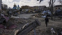 Seorang jurnalis berjalan di tengah kehancuran setelah serangan Rusia di Byshiv di pinggiran Kyiv, Ukraina, Minggu, (27/3/2022). (AP Photo/Rodrigo Abd)