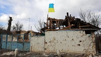 Bendera Ukraina dipasang di gedung apartemen yang rusak akibat pertempuran antara pasukan Rusia dan Ukraina di desa Lukyanivka, wilayah Kyiv, Ukraina, Minggu, (27/3/2022). (AP Photo)