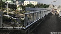 Warga melintas di JPO yang sebagian pagarnya hilang.