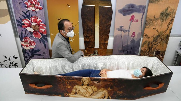 A worker moves a paper coffin at the factory of LifeArt in Hong Kong, Friday, March 18, 2022. Hong Kong is running short of coffins during its deadliest outbreak of the coronavirus pandemic. LifeArt, a company in Hong Kong is trying to make an alternative, cardboard coffin, which it says is environmentally-friendly. (AP Photo/Kin Cheung)