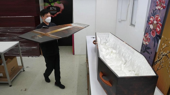 A worker moves a paper coffin at the factory of LifeArt in Hong Kong, Friday, March 18, 2022. Hong Kong is running short of coffins during its deadliest outbreak of the coronavirus pandemic. LifeArt, a company in Hong Kong is trying to make an alternative, cardboard coffin, which it says is environmentally-friendly. (AP Photo/Kin Cheung)