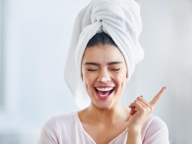 Shot of a beautiful young woman applying moisturizer to her skin in the bathroom at home