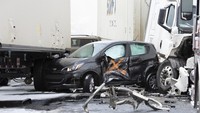 Sebuah mobil tampak terjepit di antara trailer traktor akibat kecelakaan beruntun yang terjadi di Interstate 81 North dekat pintu keluar Minersville di Foster Township, Pennsylvania, Amerika Serikat, Senin (28/3/2022) waktu setempat.