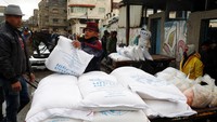 Pekerja Palestina memuat karung tepung di atas kereta kuda yang diterima pengungsi dari gudang Badan Bantuan dan Pekerjaan PBB, (UNRWA), di kamp pengungsi Shati, di Kota Gaza. Ukraina dan Rusia menyumbang sepertiga dari ekspor gandum dan jelai global, yang diandalkan negara-negara di Timur Tengah untuk memberi makan jutaan orang yang hidup dari roti bersubsidi dan mi murah. (AP/Adel Hana)