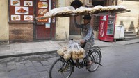 Seorang pedagang menyeimbangkan nampan roti pipih tradisional Mesir Baladi saat ia bersepeda di distrik Old Cairo, Mesir. Para ahli mengatakan mereka khawatir bahwa masalah keamanan pangan di Timur Tengah akibat perang di Ukraina dapat memicu meningkatnya kerusuhan sosial di negara-negara yang sudah di ambang kehancuran. Di Irak dan Sudan, frustrasi publik pada harga pangan dan kurangnya layanan pemerintah meletus dalam protes jalanan pada beberapa kesempatan selama beberapa minggu terakhir. (AP/Amr Nabil)
