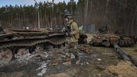 Tentara Ukraina melintasi tank Rusia yang hancur dalam pertempuran di  Stoyanka, Minggu (27/3/2022).  (AP Photo/Vadim Ghirda)