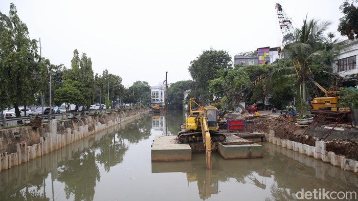 Pekerja dengan menggunakan alat berat memasang turap di pinggir Kali Ciliwung di kawasan Pasar Baru, Jakarta Pusat, Rabu (30/3/2022).